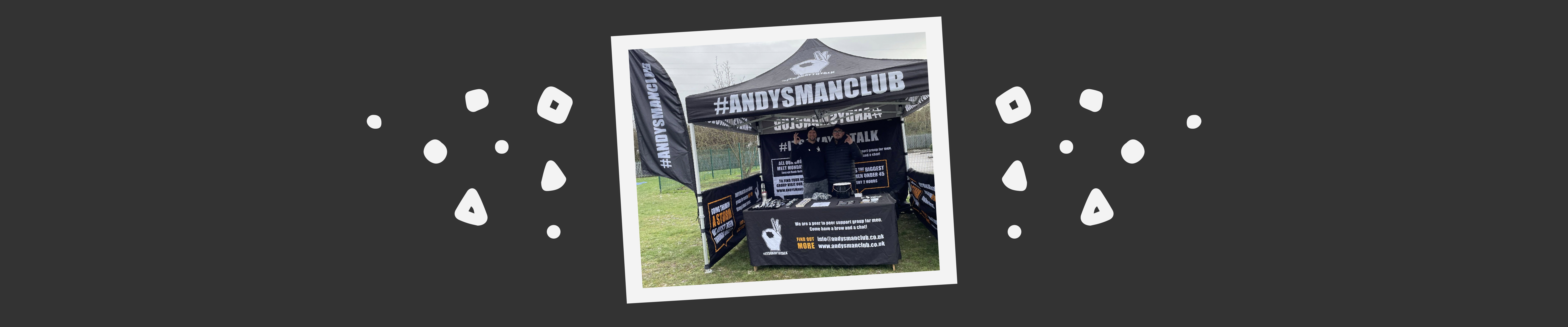 ANDYSMANCLUB volunteers stood under a branded tent at an outdoor event